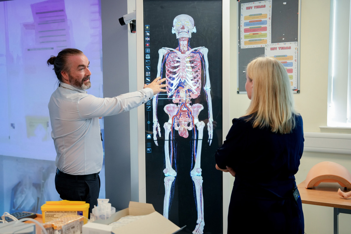 Man points at diagram of human body and skeleton 
