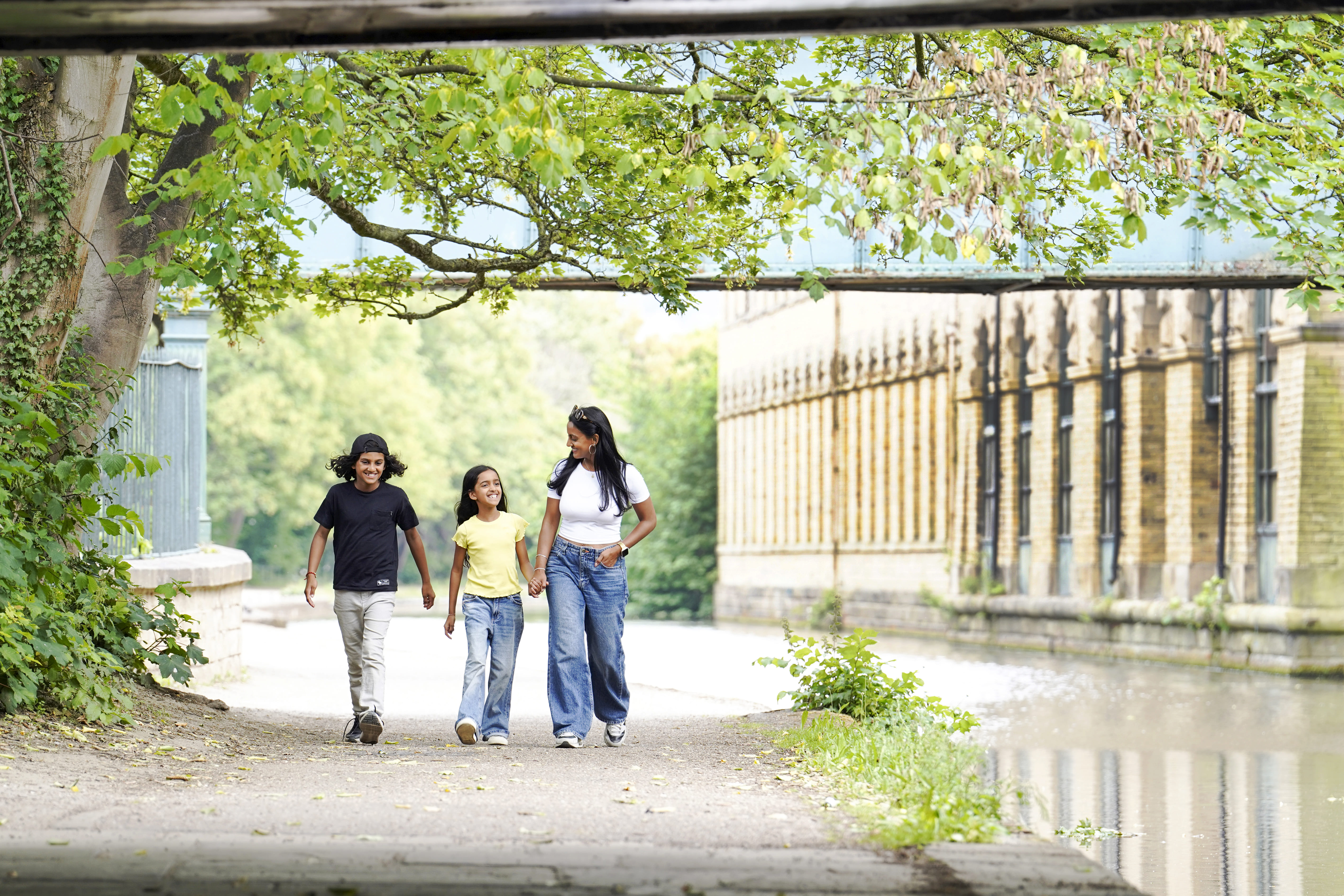 Family walking along towpath beside canal in Saltaire