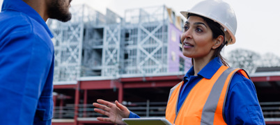 Construction engineers wearing hard hats holding clipboards