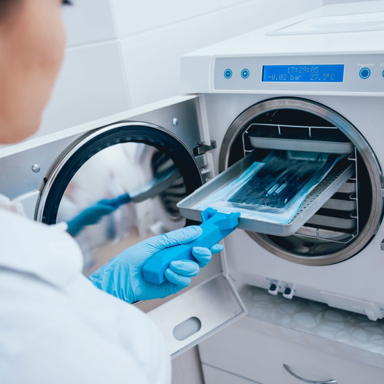 A woman sterilizing medical instruments in an autoclave
