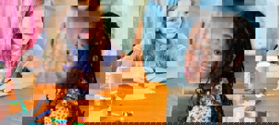 Children smiling at table doing crafts and colouring