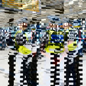 Three police officers speaking together and smiling in Leeds bus station