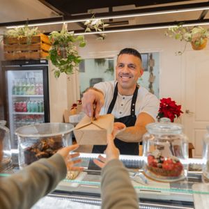 Business Owner Of A Coffee Shop Serving A Customer