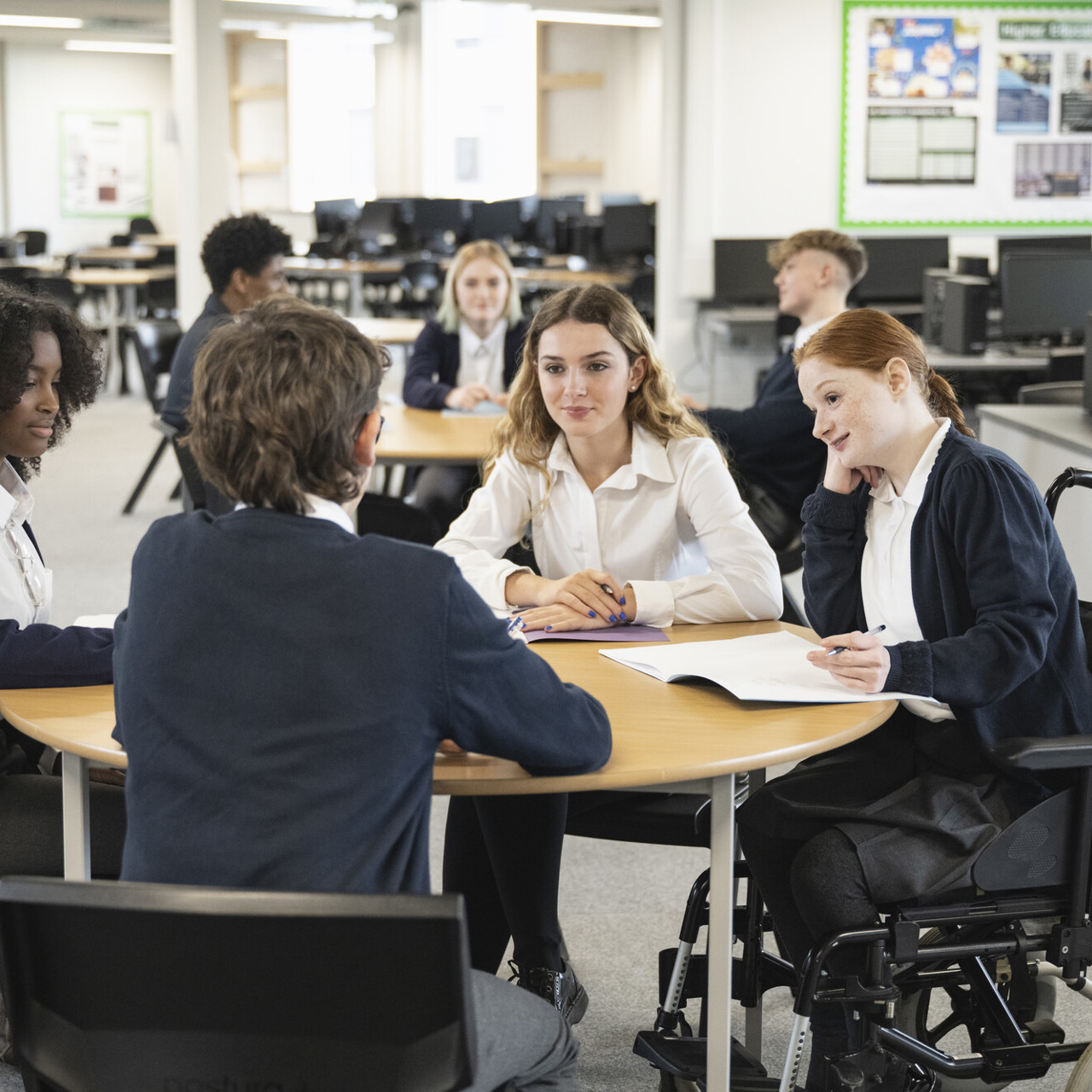 School children sitting round a desk in a study space