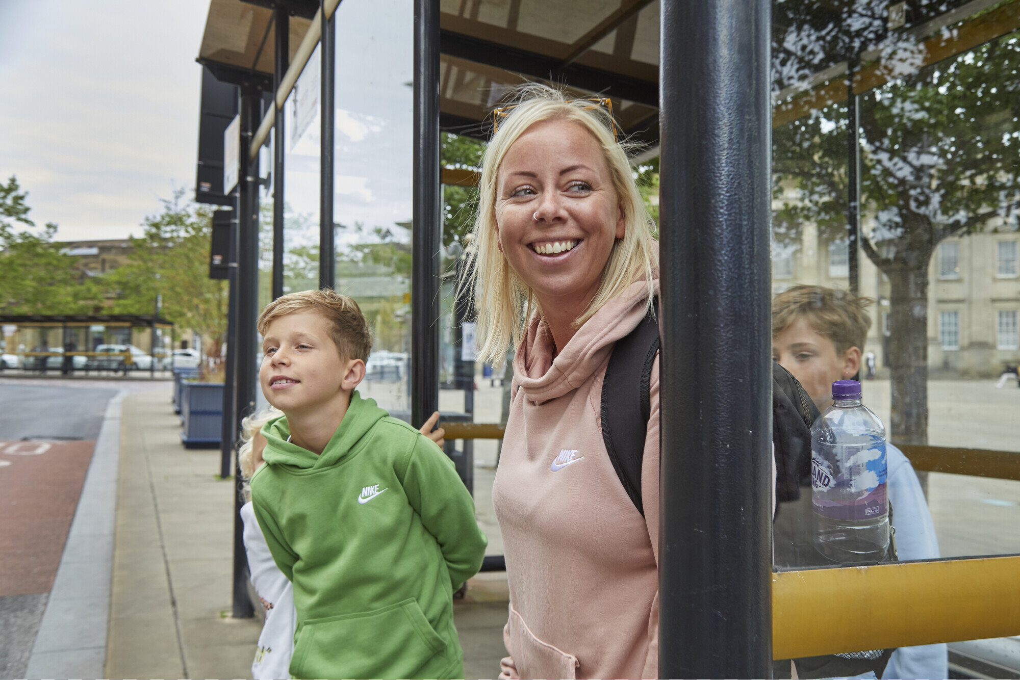 Smiling family waiting in a bus shelter for a bus in Huddersfield