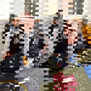 Two ladies laughing with a range of printed merchandise in front of them