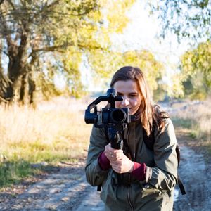 Female Videographer Holding A Gimbal With Camera, Filming Outdoors On A Sunny Afternoon