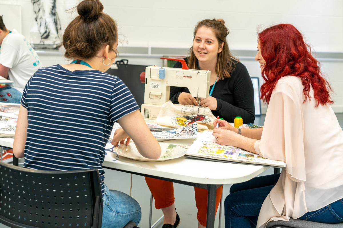 Students sewing together at table 