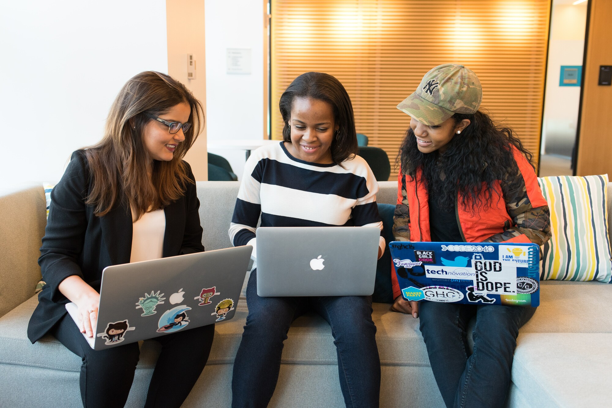 Group of students sitting together with laptops, smiling